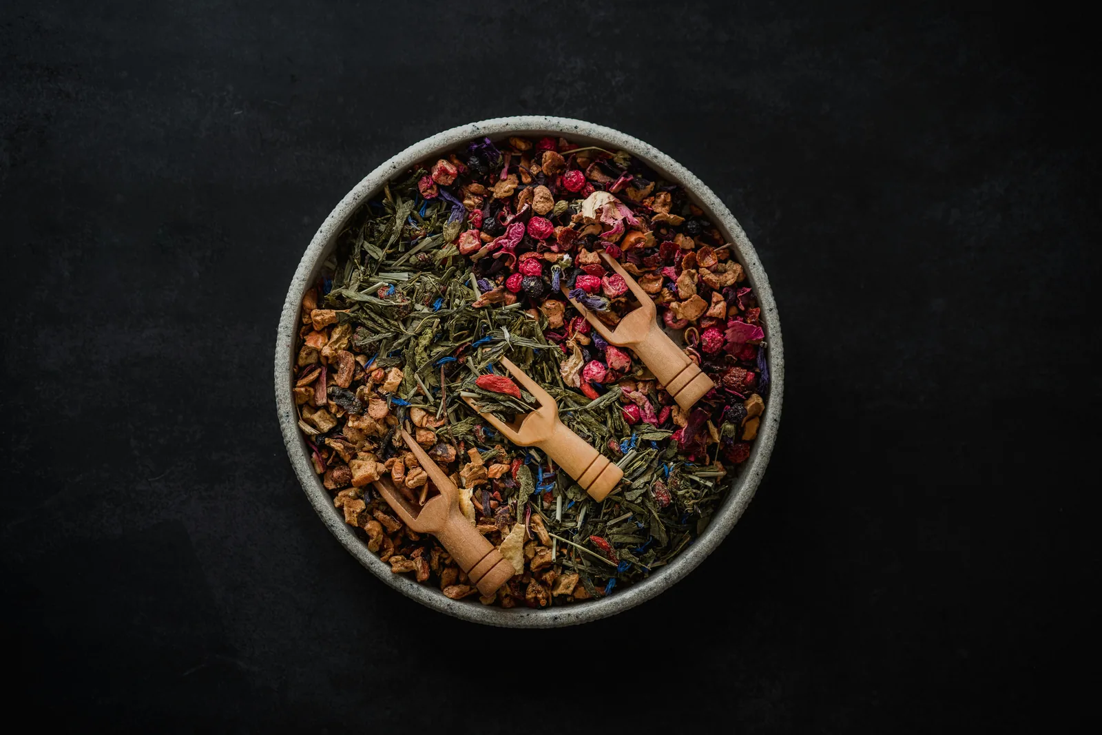 A bowl of loose-leaf herbal tea blend with dried fruit and flower pieces